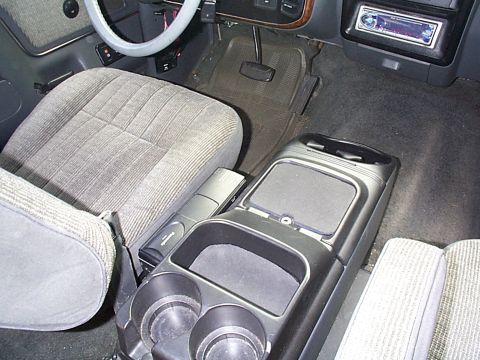 1991 Ford Bronco - The interior of the vehicle features cloth seats and a prominent center console with storage and cup holders.
