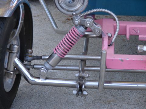 1973 Ford Ranchero - The front suspension of a custom-built trike features a pink coilover shock and polished metal components.