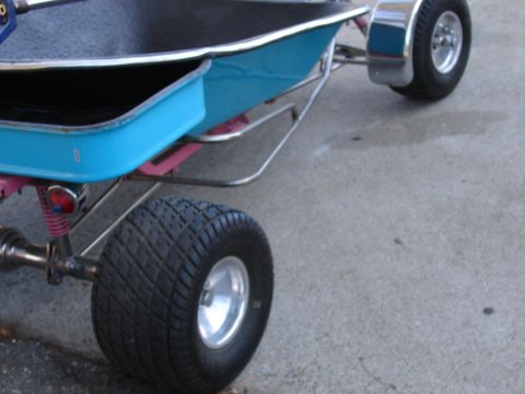 1973 Ford Ranchero - A custom trailer with a bright blue body, chrome fenders, and large tires is parked on a concrete surface.
