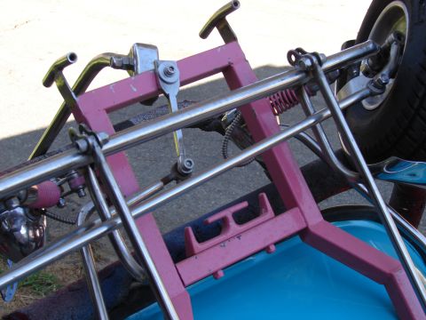 1973 Ford Ranchero - Close-up view of a custom pink and chrome frame with a blue seat and a tire, possibly part of a go-kart or custom vehicle.