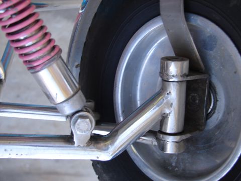 1973 Ford Ranchero - Chrome swingarm and pink shock absorber on a motorcycle's rear wheel assembly.