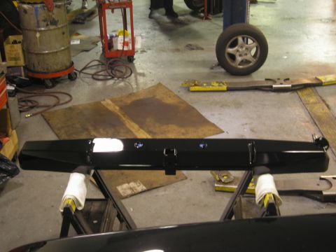 1995 Ford Bronco - A black rear bumper assembly, likely for a truck or SUV, is displayed on a stand in a workshop setting.