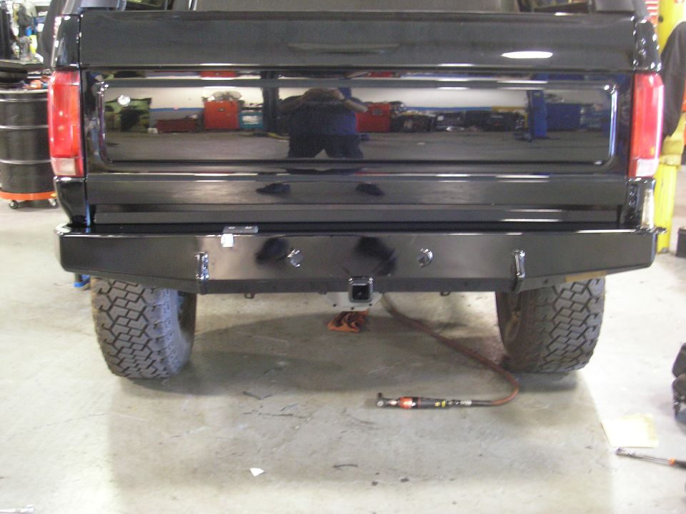 Rear of black Ford Bronco with custom steel rear bumper and hitch in a shop