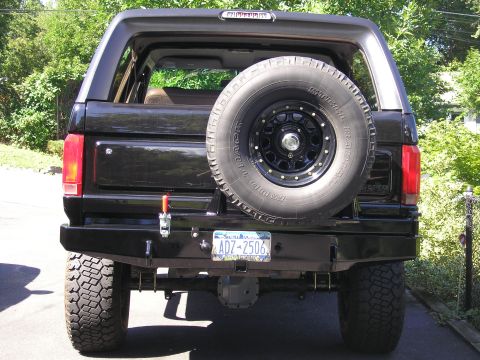 1995 Ford Bronco - Rear view of a black 1995 Ford Bronco, an aftermarket bumper and a spare tire mounted on the tailgate.