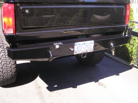 1995 Ford Bronco - The rear bumper of a black vehicle features a trailer hitch and a license plate.