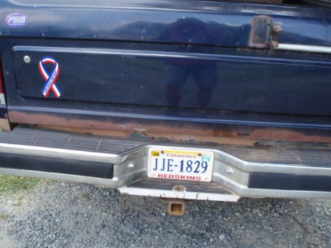 1989 Ford Bronco - Rear view of a 1989 Ford Bronco showing the bumper, license plate, and a decorative ribbon sticker.