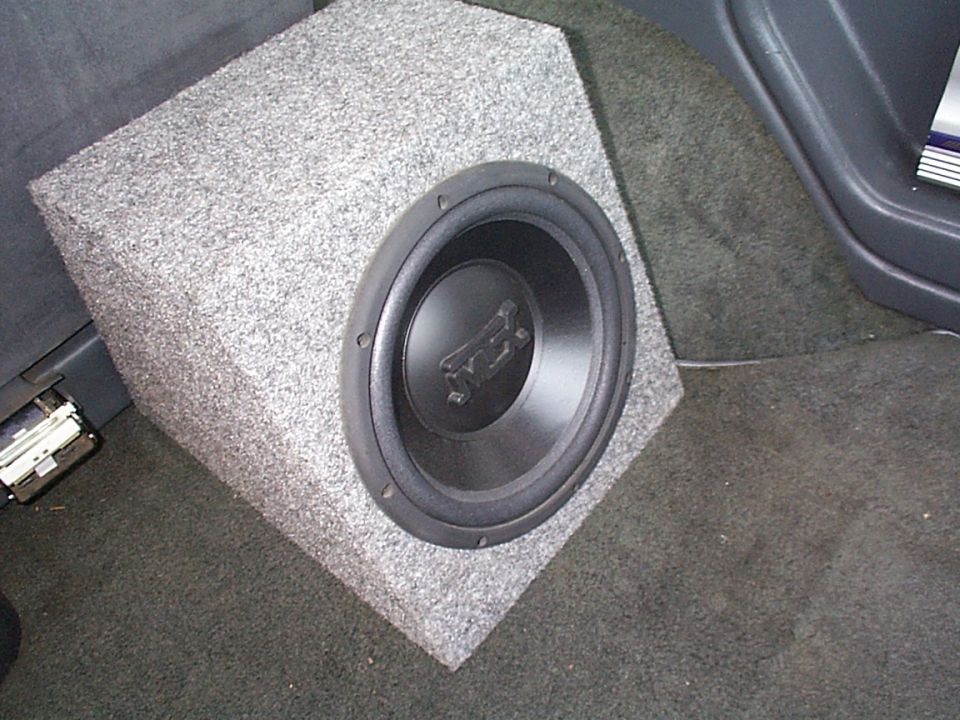 Car subwoofer in a carpeted enclosure, seen from the side