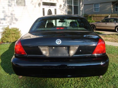 1993 Ford Crown Victoria - Rear view of a black Mercury Marauder sedan parked on grass, showing the Mercury emblem on the trunk, chrome-trimmed taillights, an empty l…