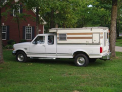 1980 Ford Bronco - Side view of a white pickup truck fitted with a camper shell.