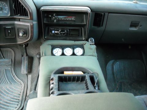 1990 Ford C-150 (Centurion Conversions) - The interior of a vehicle shows a center console equipped with three gauges, suggesting a custom or specialized setup.