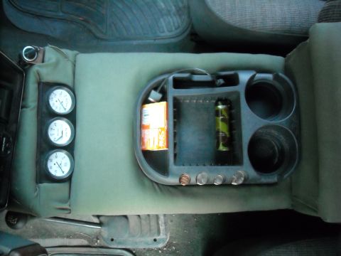 1990 Ford C-150 (Centurion Conversions) - The center console of a vehicle features auxiliary gauges and storage compartments.