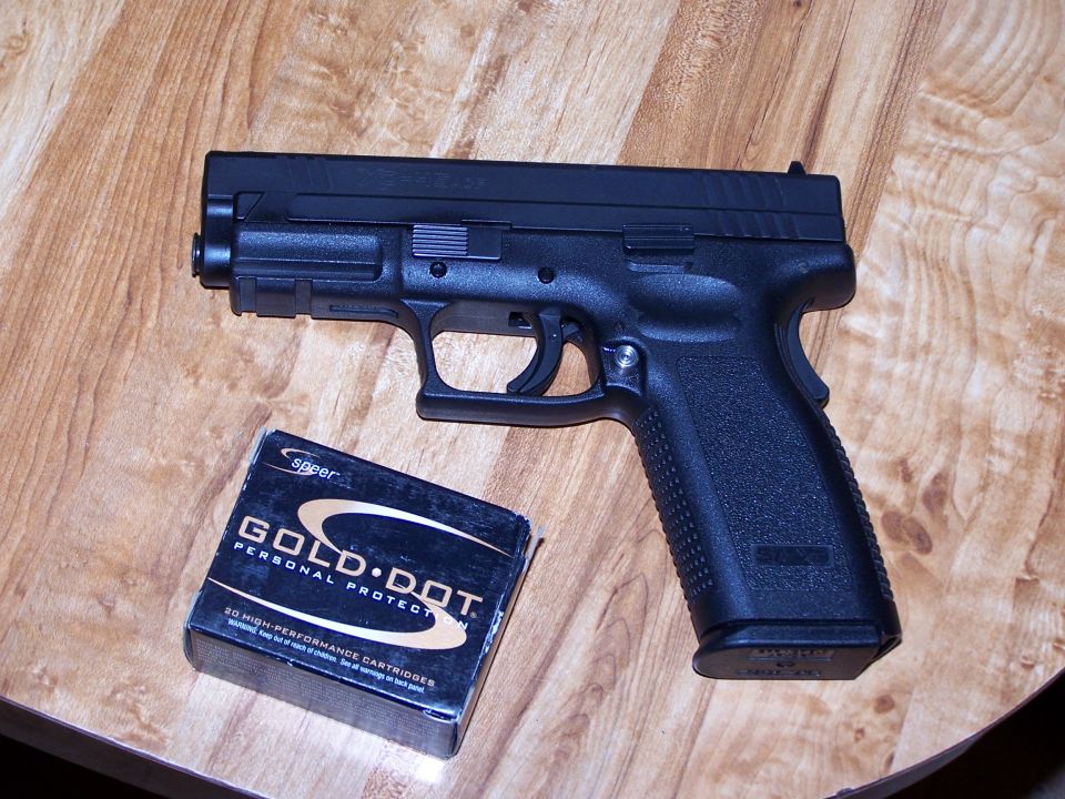 Black pistol next to a box of Speer Gold Dot personal protection cartridges