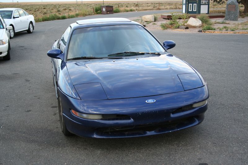 Blue 1995 Ford Probe parked on asphalt, with a white sedan in the background