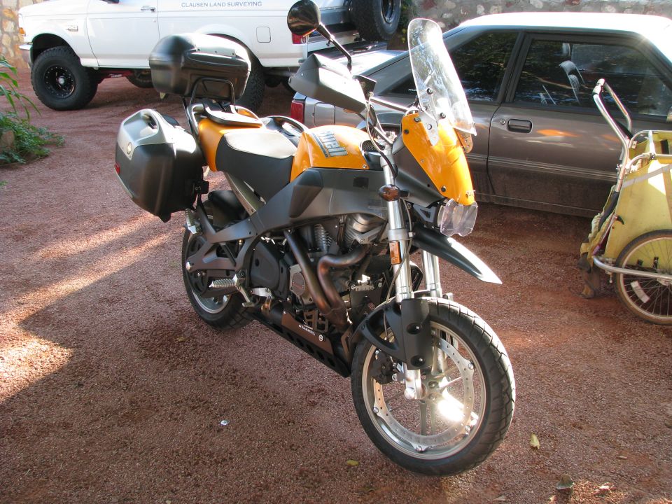 Yellow Buell adventure-style motorcycle with luggage cases parked on gravel