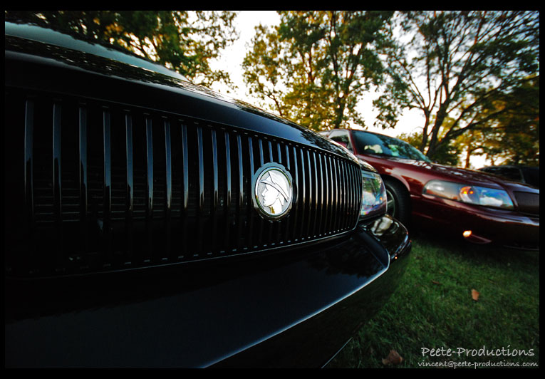 Black 2003 Mercury Marauder grille with Mercury emblem, red car behind