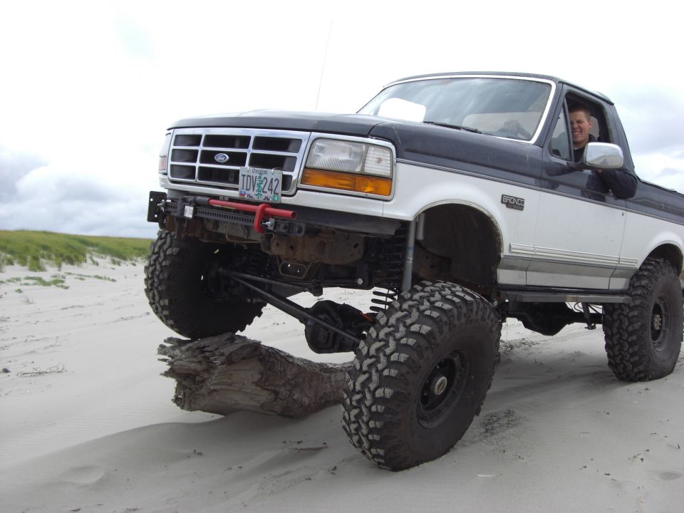 1992 Ford Bronco, lifted, two-tone white and black, driving on sand with large tires