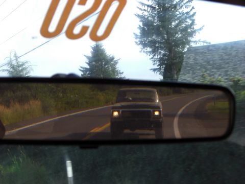 1993 Ford Bronco - A dark Ford F-Series truck is seen in the rearview mirror while driving on a two-lane road.