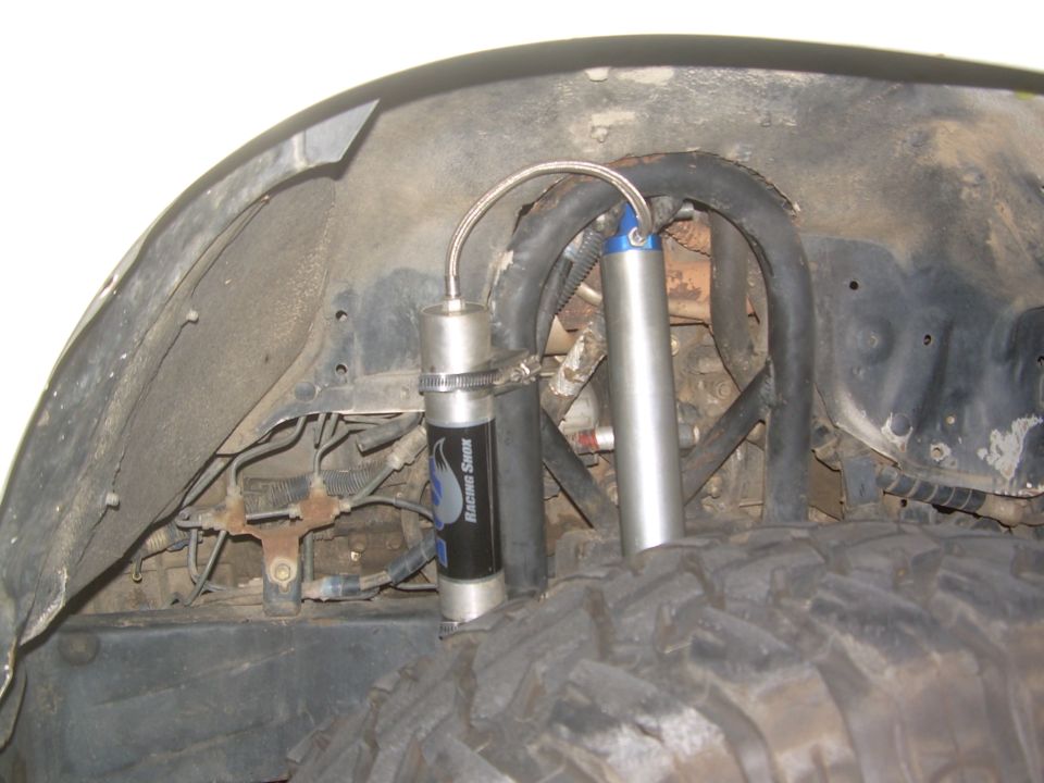 Close-up of off-road suspension with two shock absorbers and hoses, one labeled 'Racing Swen'