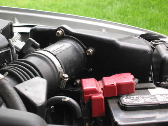 Engine bay with air intake tubing and red-capped battery terminals