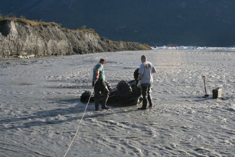 1990 Chevrolet Suburban - Men attempt to recover an ATV stuck in a muddy riverbed with a shovel and toolbox at the ready.
