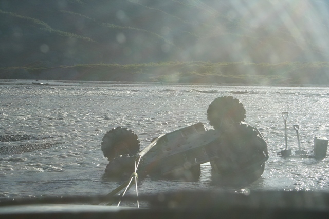 Vehicle overturned in shallow river with two shovels nearby