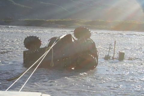 1990 Chevrolet Suburban - Vehicle recovery operation in shallow water with shovels and bucket nearby.
