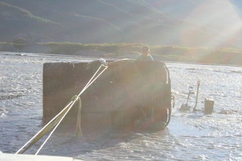 1990 Chevrolet Suburban - Vehicle stuck in river with shovels nearby.