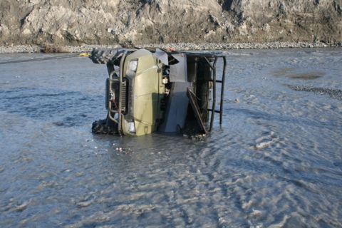 1990 Chevrolet Suburban - An ATV is submerged and overturned in a river, with a tow cable attached.