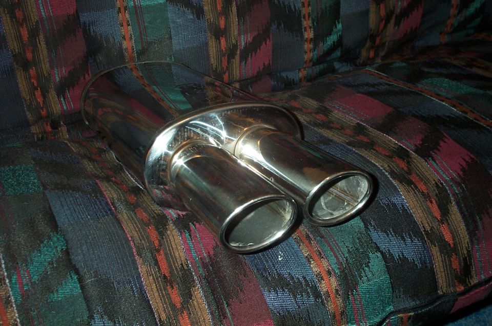 Polished stainless dual-tip exhaust muffler on plaid fabric