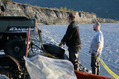 1990 Chevrolet Suburban - Two men stand by a river next to a Polaris Ranger ATV, possibly preparing for recovery.