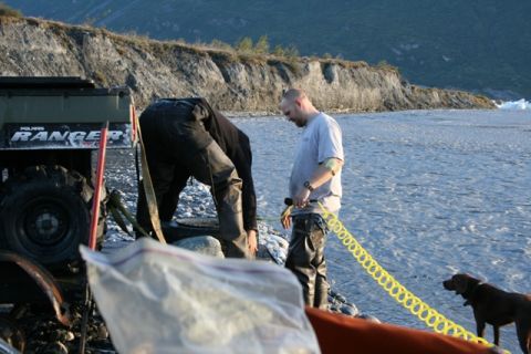 1990 Chevrolet Suburban - A Polaris Ranger ATV is partially visible next to a riverbank where two people and a dog are present.