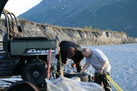 1990 Chevrolet Suburban - Two men work near a Polaris Ranger ATV on a rocky shore with a mountain in the background.