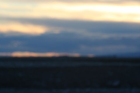 1990 Chevrolet Suburban - The image is out of focus and shows a blurry landscape with clouds at sunset or sunrise.