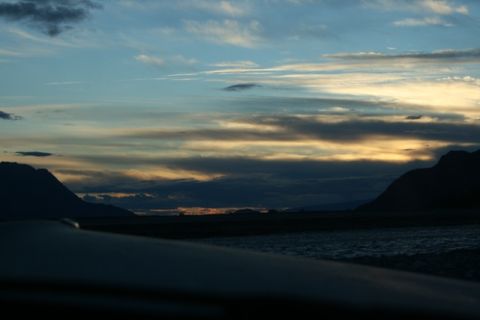 1990 Chevrolet Suburban - A wide shot of a river and mountains under a cloudy sky at dusk.