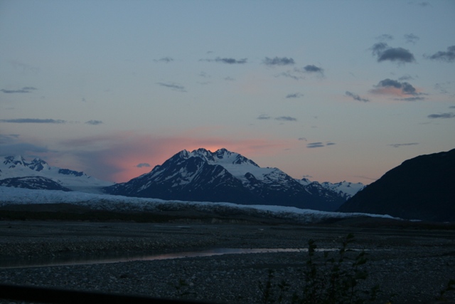 Mountain range at dusk with a pink sunset behind the central peak.
