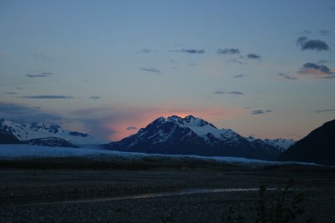 1990 Chevrolet Suburban - A mountain range with snow-capped peaks is illuminated by the setting sun, casting a warm glow on the clouds behind the central peak. The f…