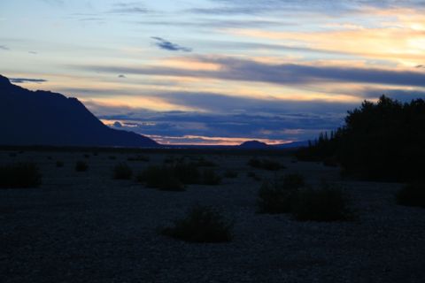 1990 Chevrolet Suburban - A wide shot of a desolate landscape at dusk with mountains in the distance and a treeline on the right.