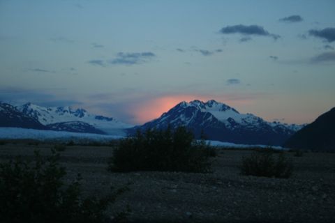1990 Chevrolet Suburban - A mountain range with snow-capped peaks is illuminated by the setting sun, casting a warm glow on the central mountain. The foreground is a…