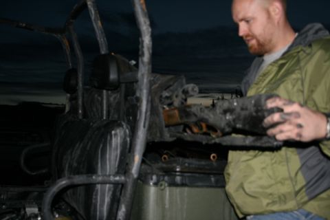 1990 Chevrolet Suburban - A man in a green jacket holds a charred, melted piece of what appears to be a vehicle's interior or engine component. The background shows…
