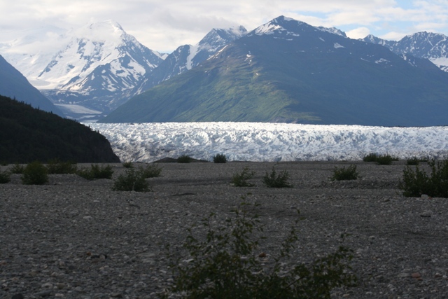 Glacier and snow-capped mountains with a rocky foreground.
