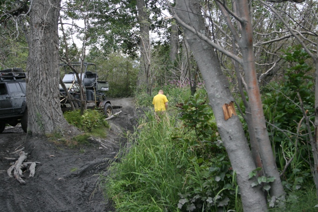 Dark SUV on a muddy trail with a person walking away.