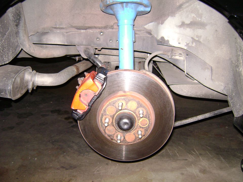 Close-up of a vehicle's rear brake caliper and rotor.