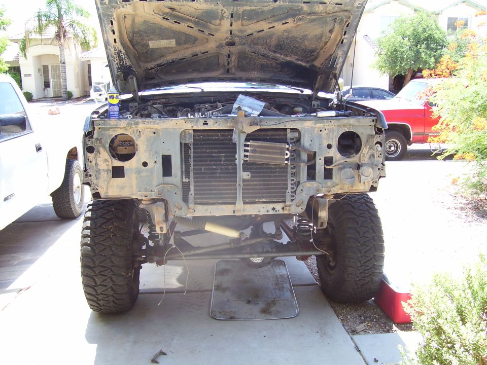 1991 Ford Bronco front end disassembled, hood open, large off-road tires, parked in driveway.
