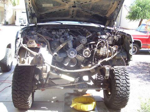 1991 Ford Bronco - The engine bay of a 1991 Ford Bronco is shown with the hood open, revealing the engine and surrounding components. The vehicle is parked ou…