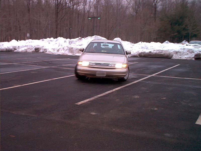 Tan Ford Crown Victoria sedan front view in an empty snowy parking lot
