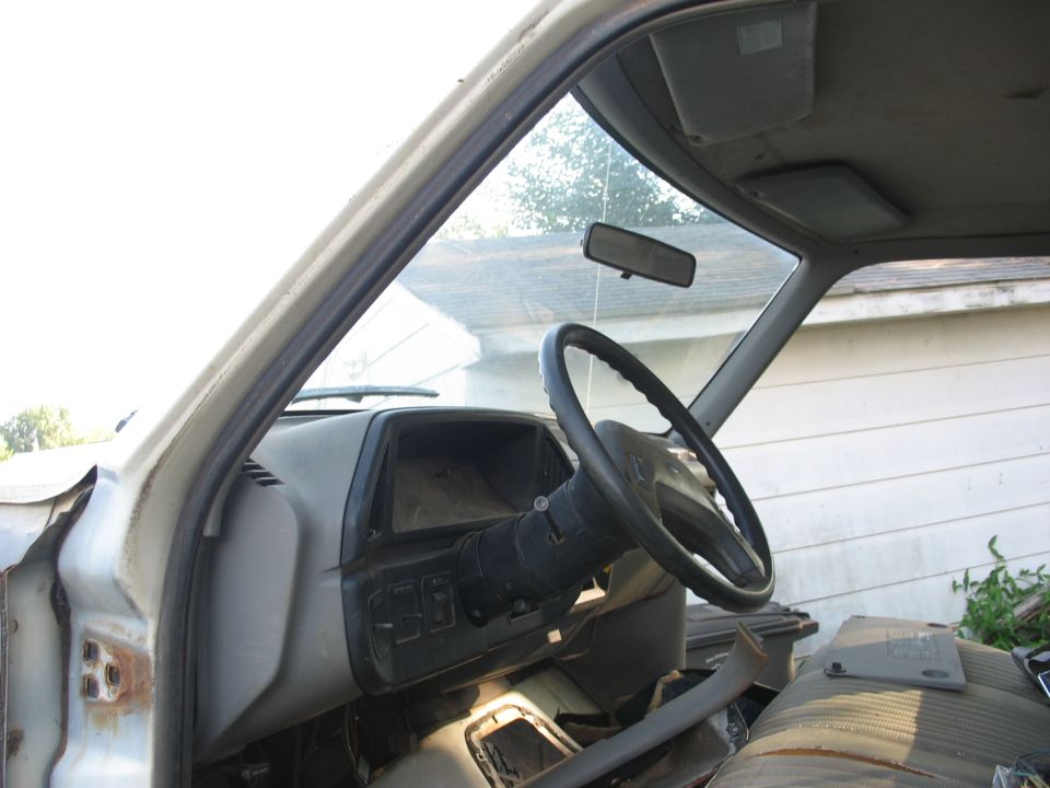 Interior view of an old van showing dashboard, steering wheel, and passenger seat.