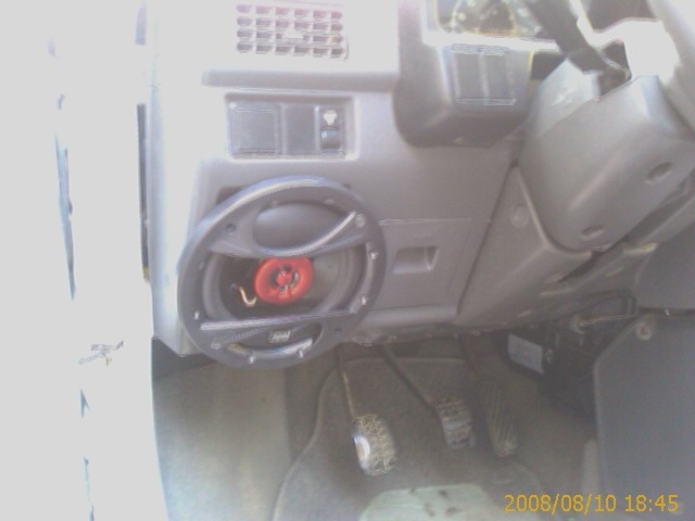 Interior view of a vehicle dashboard with a speaker and pedals.