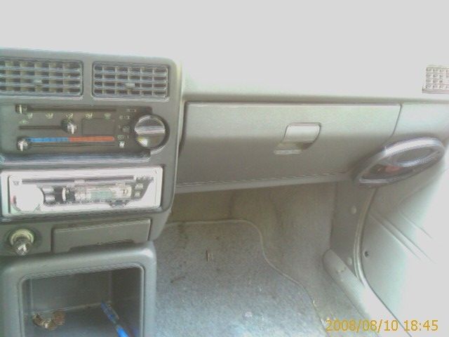 Car dashboard with radio, AC controls, and glove compartment.