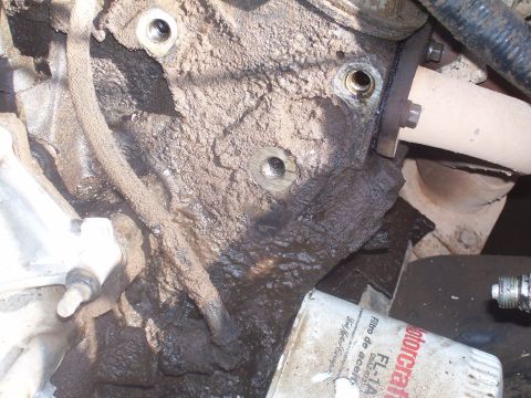 1991 Ford Bronco - A close-up view of a heavily soiled engine block with a portion of an exhaust manifold and a Motorcraft oil filter visible.