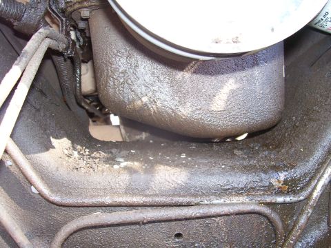 1991 Ford Bronco - This image shows the underside of a vehicle, heavily coated in oil and grime. Visible components include fuel lines, a portion of the engin…